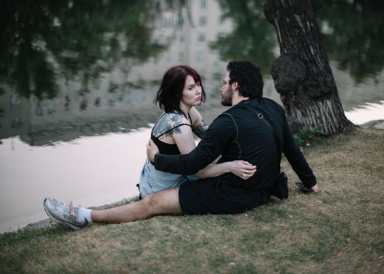 Couple sits embracing by the water and talking, representing intimacy, support, and restoring emotional connection after losing an erection during sex
